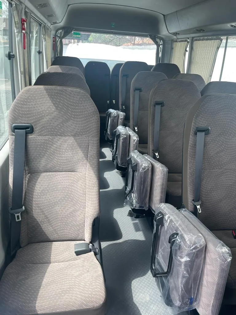 Toyota Coaster interior with cloth passenger seats and fold-down aisle seats