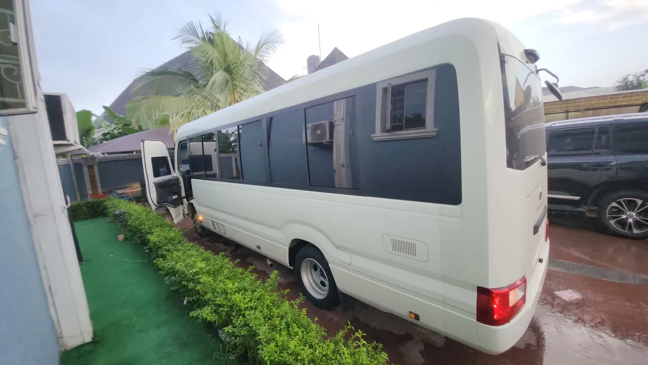 Rear three-quarter view of a new-model Toyota Coaster bus for charter in Lagos
