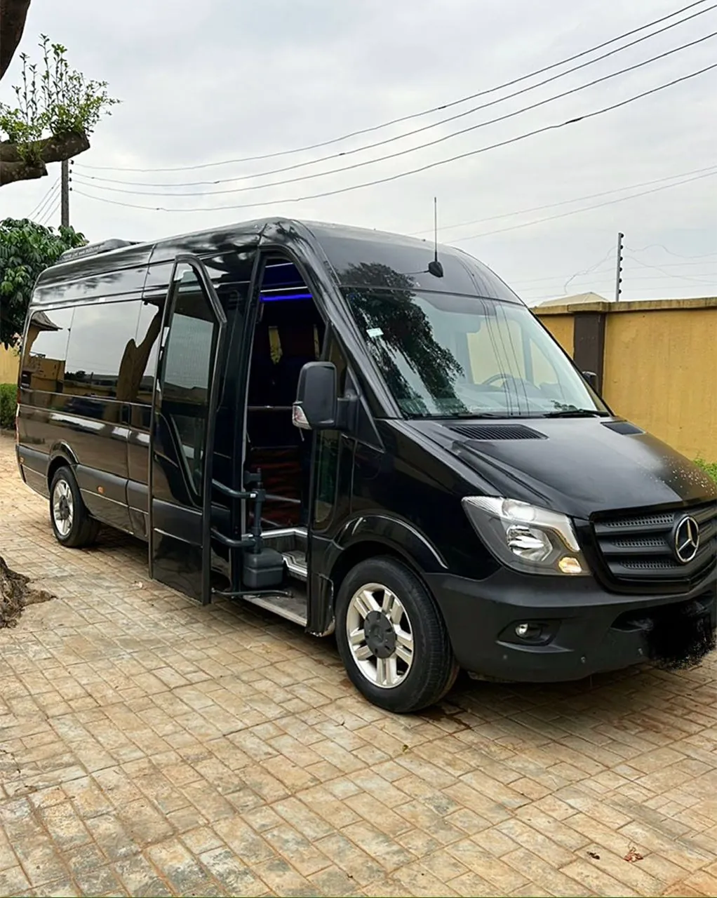 Black Mercedes-Benz Sprinter executive bus for hire in Lagos, front side view with door open